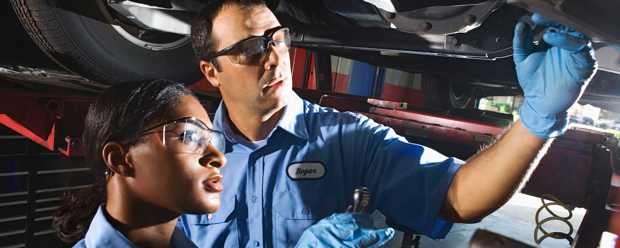 mechanics examining underside of car